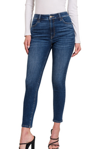 A woman wearing high waist skinny non-distressed dark wash jeggings with functional pockets.
