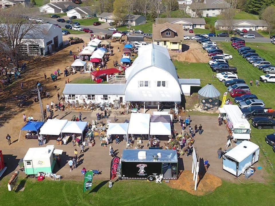 Overhead-view-from-drone-over-ReStyleandCo-with-vendor-tents-setup-in-parking-lot-and-cars-parked-in-the-field